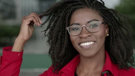 Afro-american-woman-looking-at-camera,-smiling,-correcting-hair